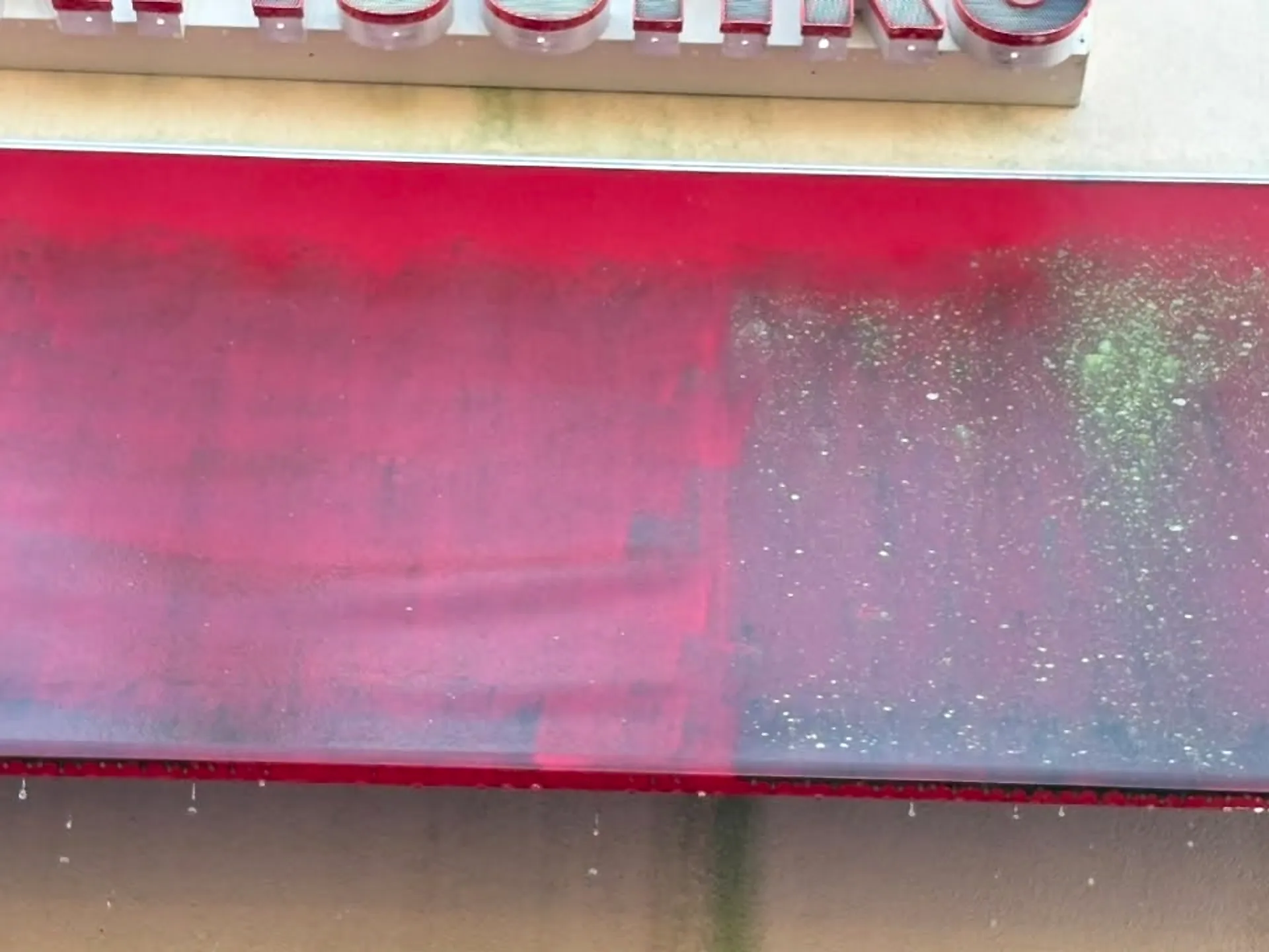A red fabric awning being rinsed down, dirt line still visible across the middle