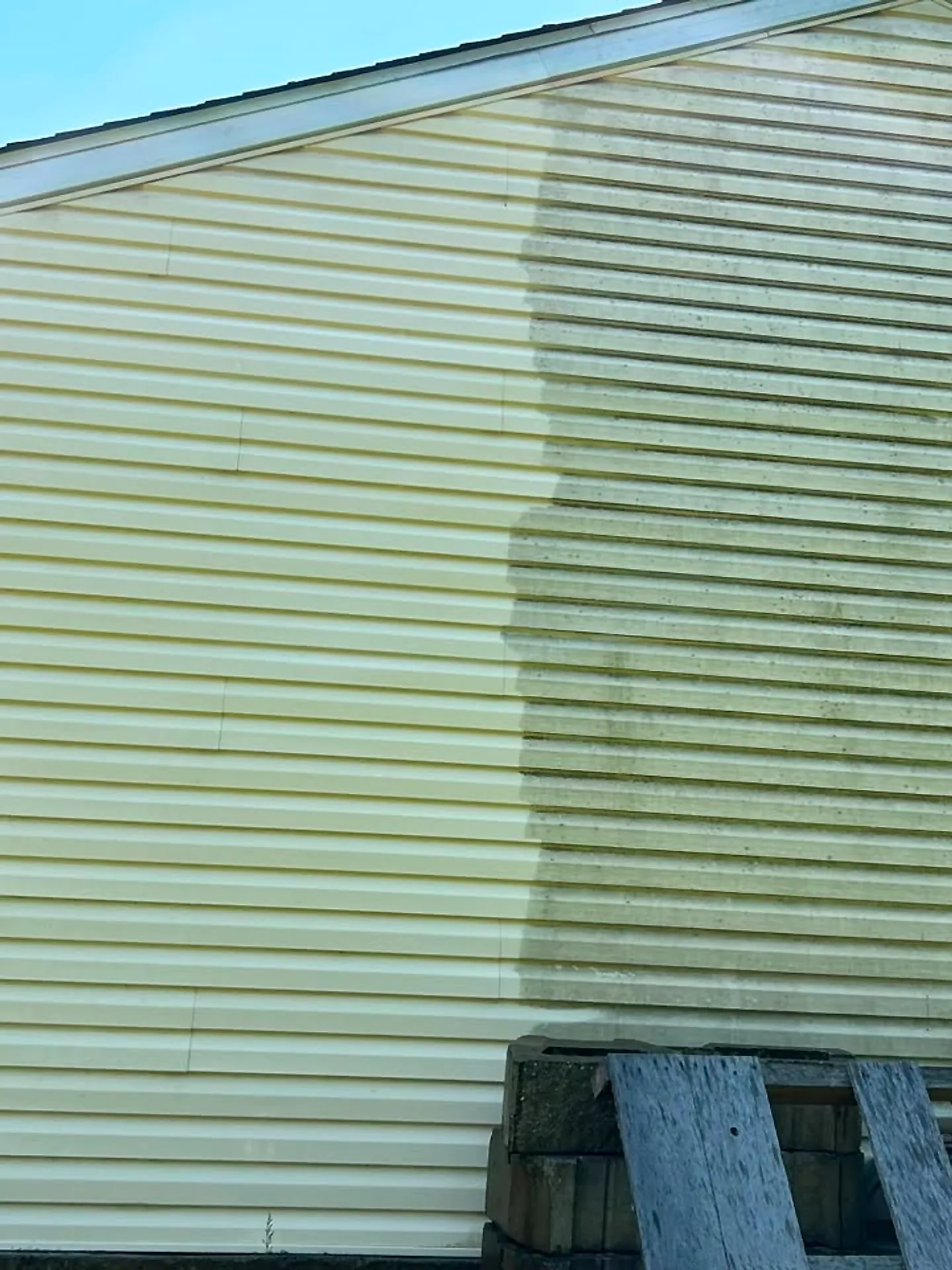 House siding mid-wash with a clear vertical line between dirty and clean