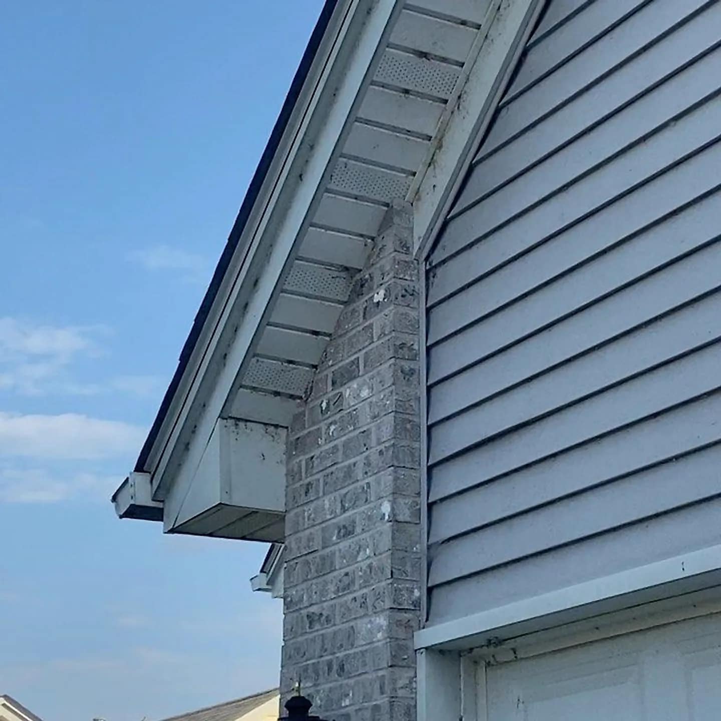 Soffit, gutter and lap siding cleaned against a clear blue sky